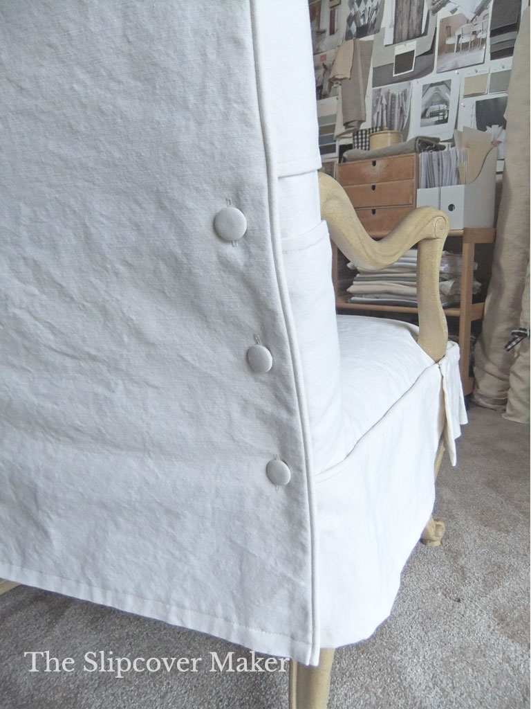 Covered buttons on a white canvas chair slipcover.