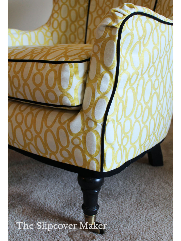 Yellow print slipcover with black welt cord detail.