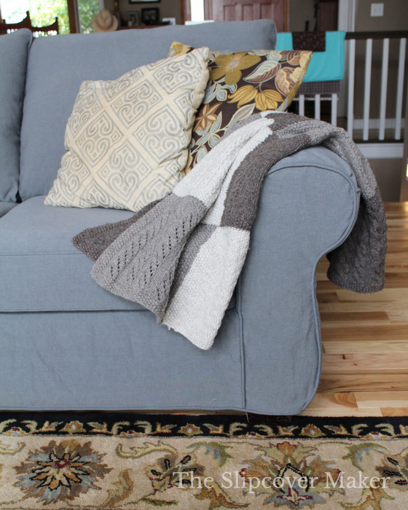 Grey Sofa with patchwork blanket and throw pillows.