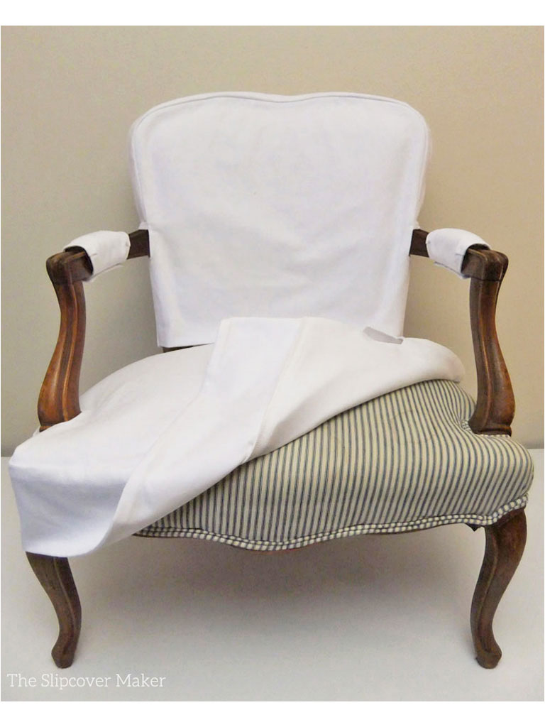 Ticking stripe upholstered French chair with white slipcover.