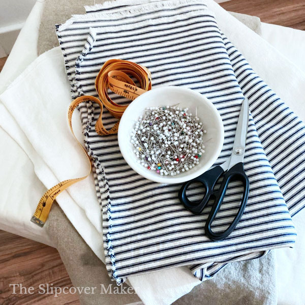 White bowl of straight pins sitting on stack of fabric. 