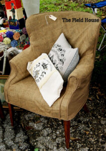 Rustic burlap slipcover on wingback chair with pillows.