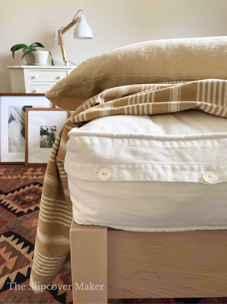 White futon with button cover sitting on bed frame.