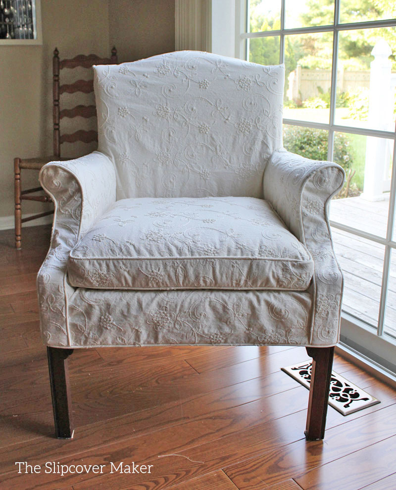 Dining chair with ivory embroidered slipcover.