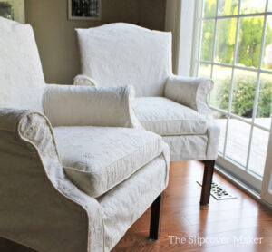 Cream color embroidered slipcovers on dining chairs.
