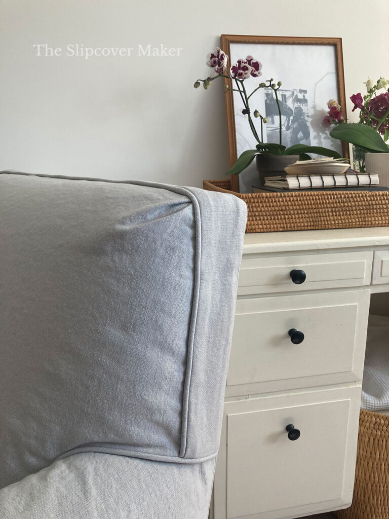 Club chair with grey slipcover next to desk.