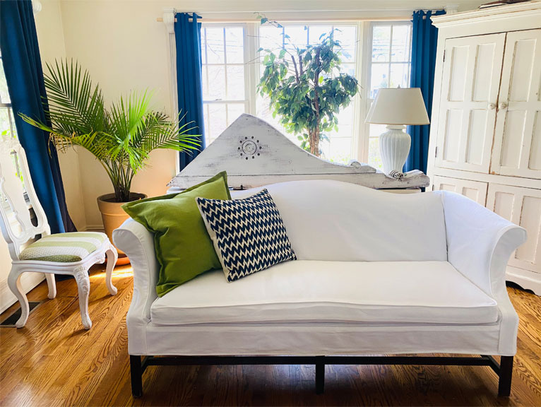 Camel back settee white slipcover in a bright room.