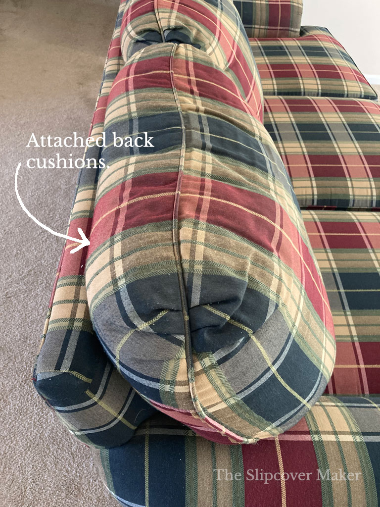 Attached back cushions on old plaid sofa.