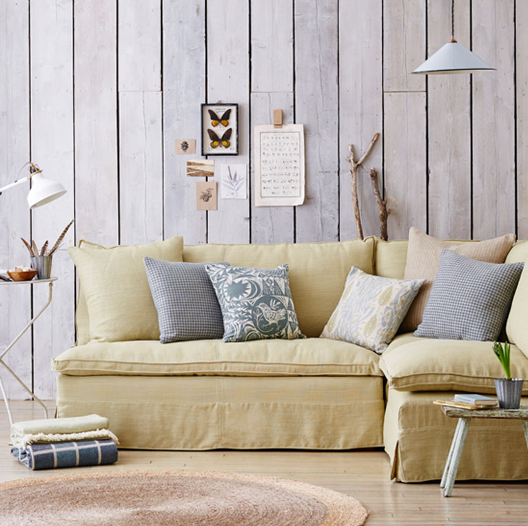 Pale yellow linen slipcovered sectional sofa.