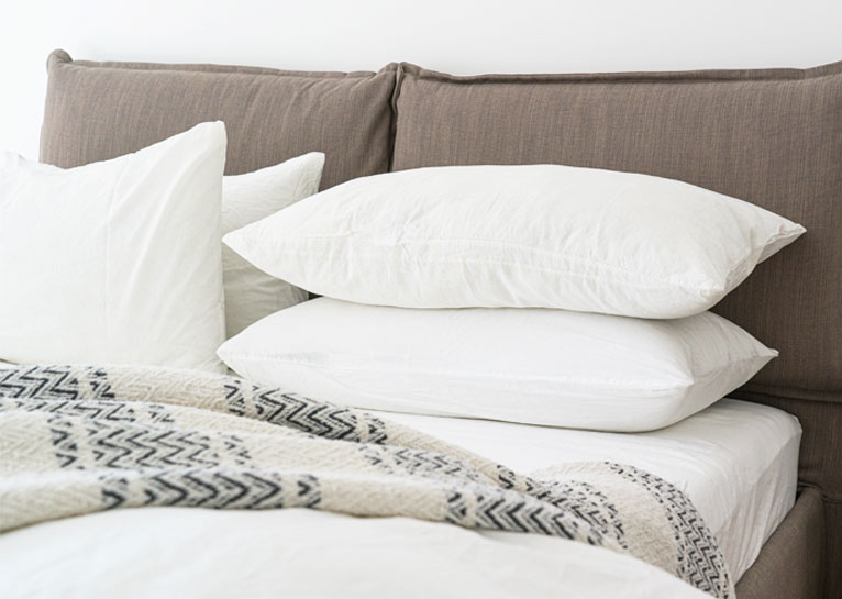 Brown linen bed headboard cover with pillows.