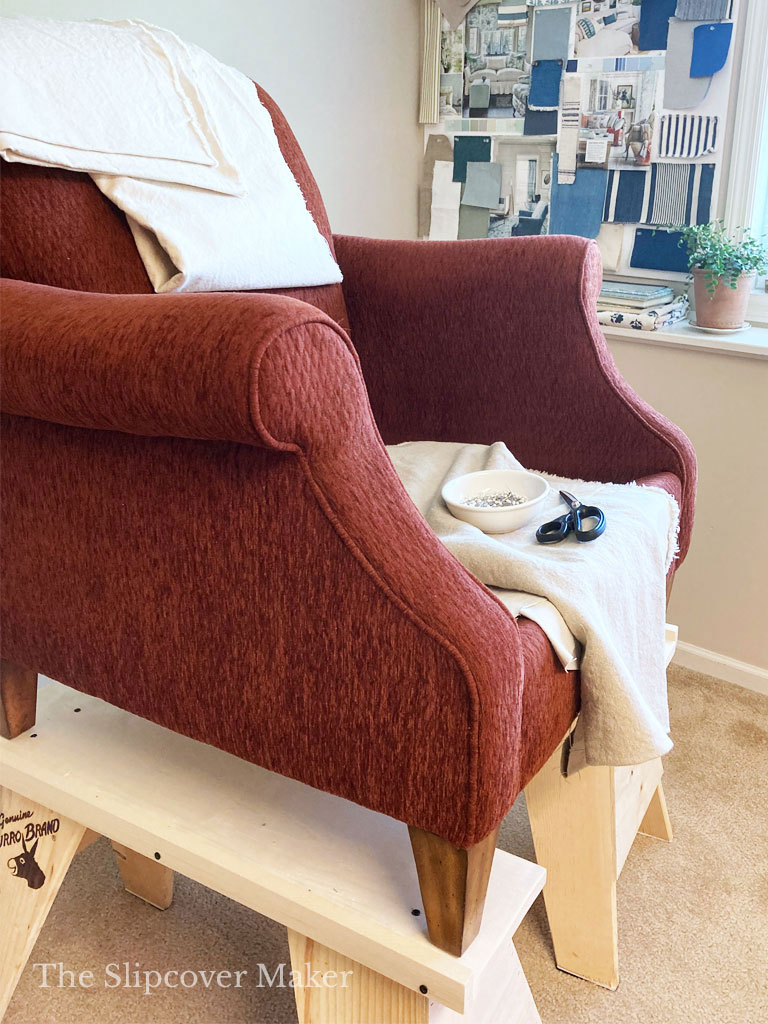 Red chair up on risers for a slipcover pin fitting.