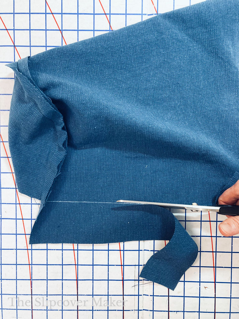 Cutting off excess hem fabric from arm cover.