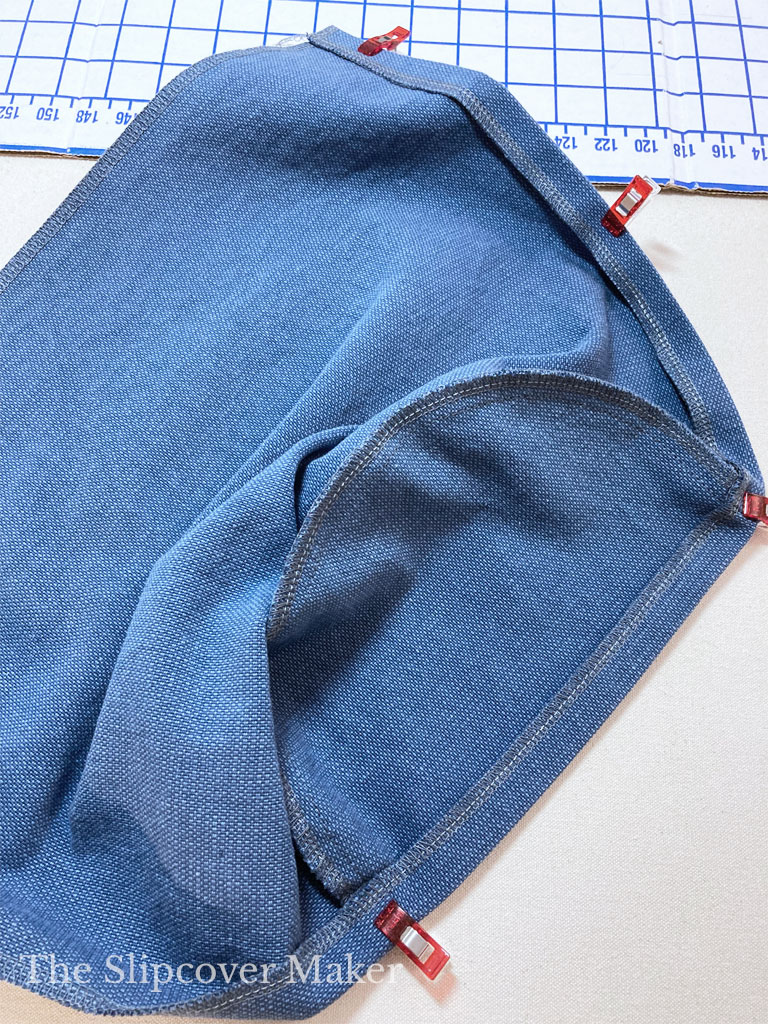 Preparing turned hem on arm cover.