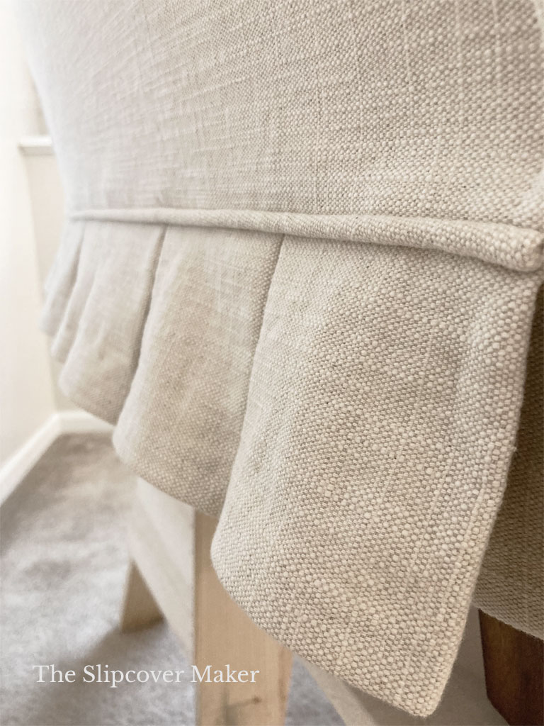 Chair slipcover with pleated skirt.