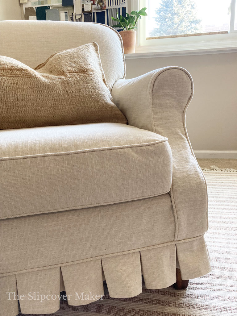 Natural cotton linen slipcover on the armchair next to window.