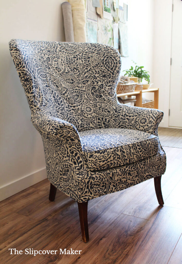 Wingback chair with blue leaf print slipcover.