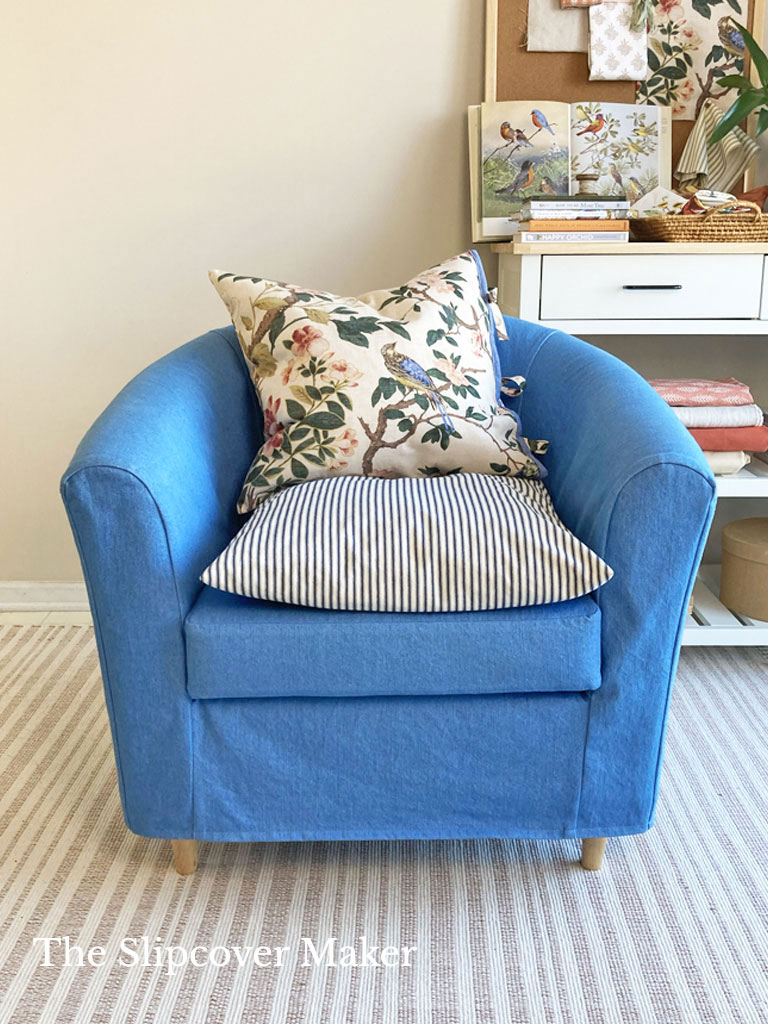 Blue denim slipcover on barrel back chair front.