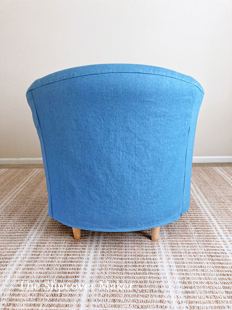 Blue denim slipcover on barrel back chair.