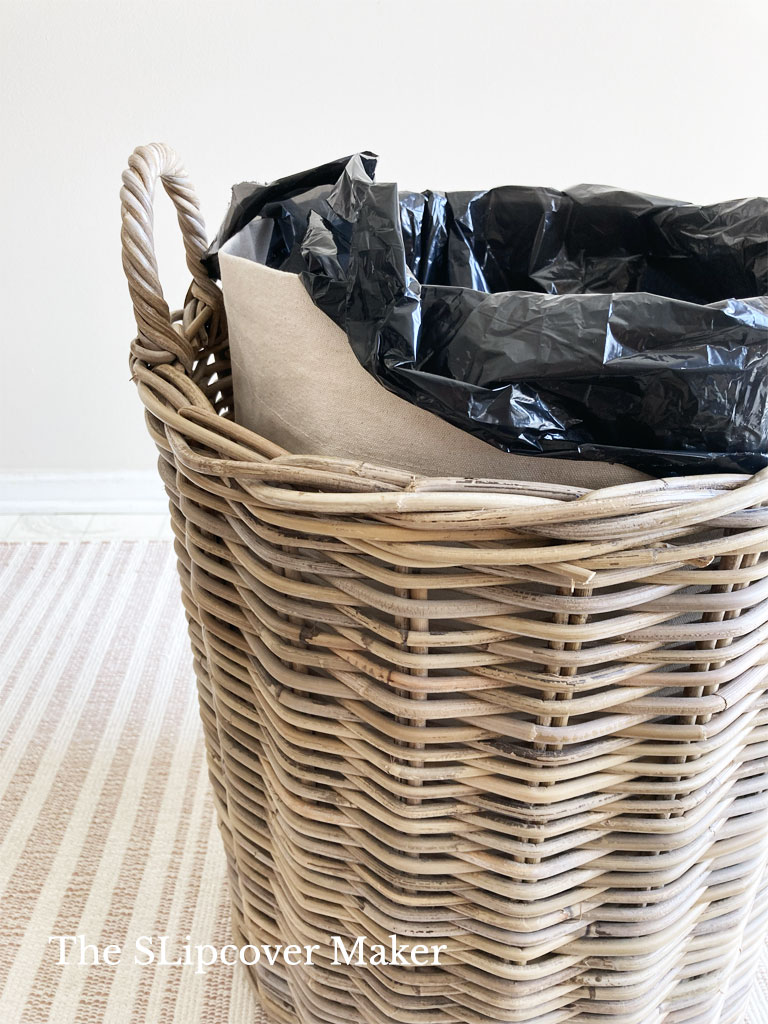 Canvas lined basket holds trash bag.