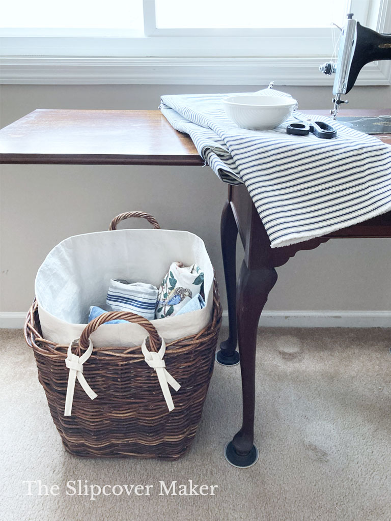 Large rattan basket with canvas liner holds fabric scraps.