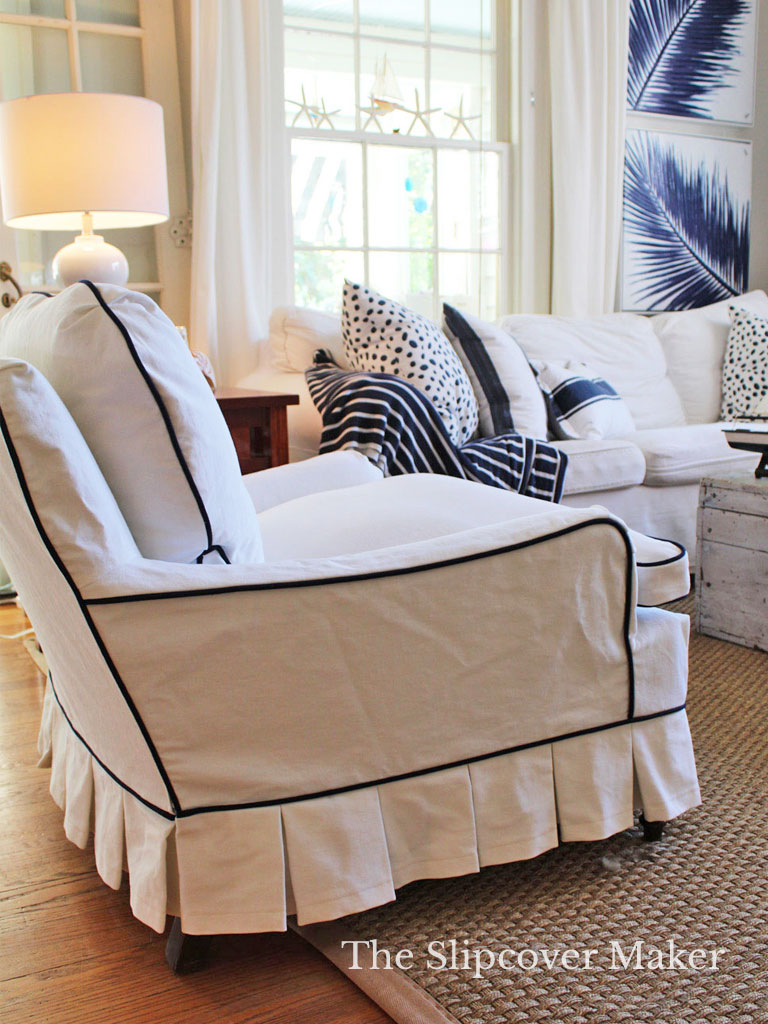 Armchair slipcovered in white denim with pleated skirt.