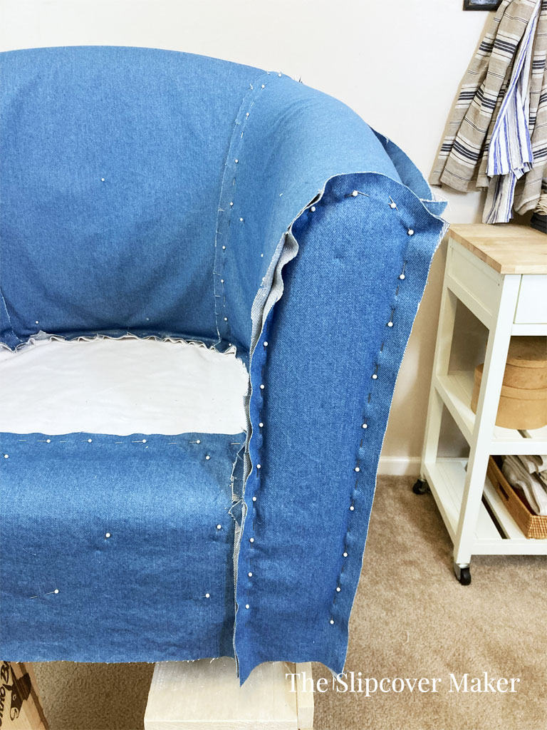 Blue denim slipcover pin fitted on a barrel back chair.